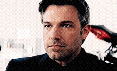 A Close Up Of A Man 'S Face With A Beard Wearing A Suit And Tie . GIF