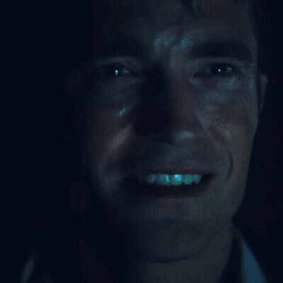 A Close Up Of A Man 'S Face With A Blue Light Shining On It GIF