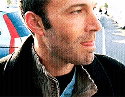 A Close Up Of A Man 'S Face With A Car Parked Behind Him GIF