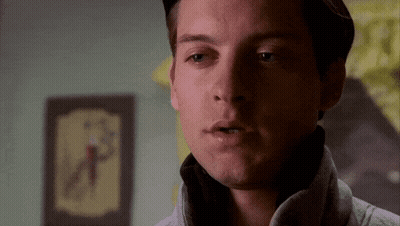 A Close Up Of A Man 'S Face With A Clock On The Wall Behind Him GIF