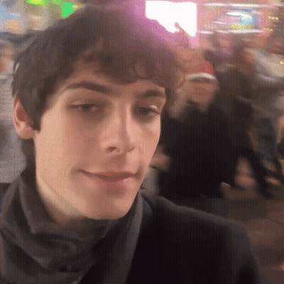 A Close Up Of A Man 'S Face With A Crowd In The Background GIF
