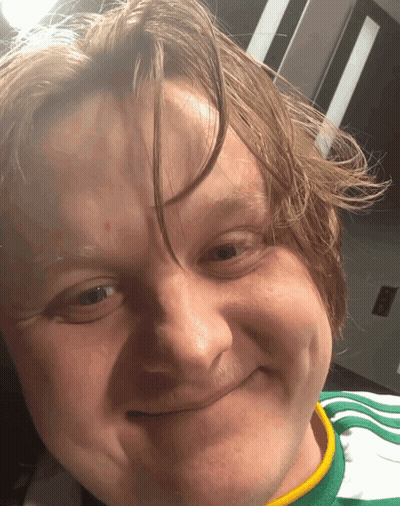 A Close Up Of A Man 'S Face With A Green And Yellow Shirt On GIF