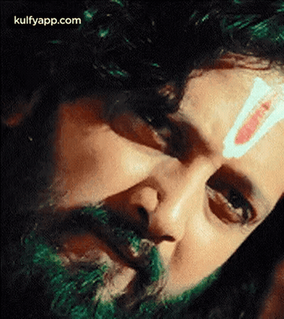 A Close Up Of A Man 'S Face With A Green Beard And A Red And White Stripe On His Forehead . GIF