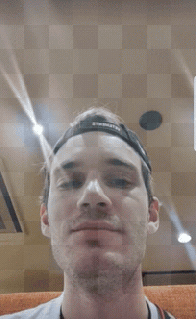 A Close Up Of A Man 'S Face With A Hat On And A Camera Around His Neck . GIF