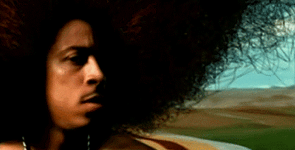 A Close Up Of A Man 'S Face With A Large Afro In Front Of A Field . GIF