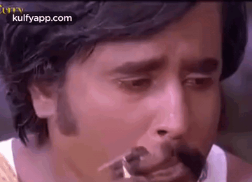 A Close Up Of A Man 'S Face With A Mustache And A Cigarette In His Mouth . GIF