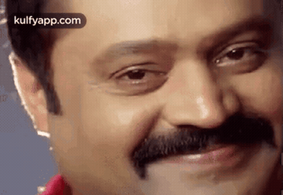 A Close Up Of A Man 'S Face With A Mustache Smiling . GIF