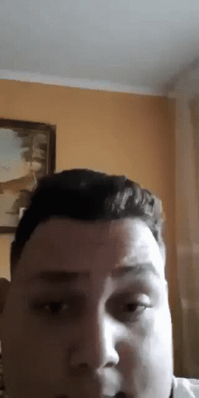 A Close Up Of A Man 'S Face With A Painting On The Wall Behind Him . GIF