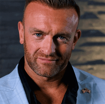A Close Up Of A Man 'S Face With A Pin On His Jacket That Says ' Usa ' GIF