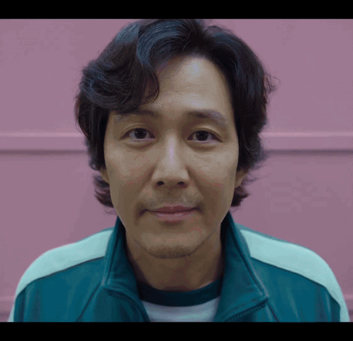 A Close Up Of A Man 'S Face With A Pink Wall Behind Him GIF