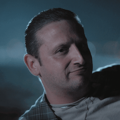 A Close Up Of A Man 'S Face With A Plaid Vest GIF