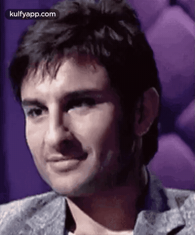 A Close Up Of A Man 'S Face With A Purple Background And A Smile . GIF
