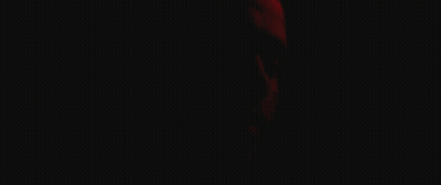 A Close Up Of A Man 'S Face With A Red Light Behind Him GIF