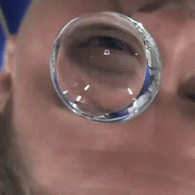 A Close Up Of A Man 'S Face With A Reflection Of Him In A Glass Ball GIF