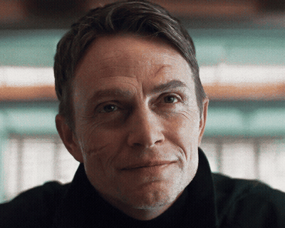 A Close Up Of A Man 'S Face With A Slight Smile On His Face GIF
