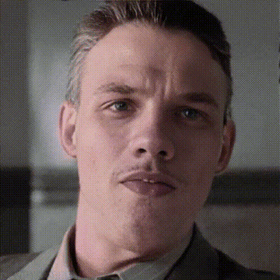 A Close Up Of A Man 'S Face With A Slight Smirk On His Face GIF