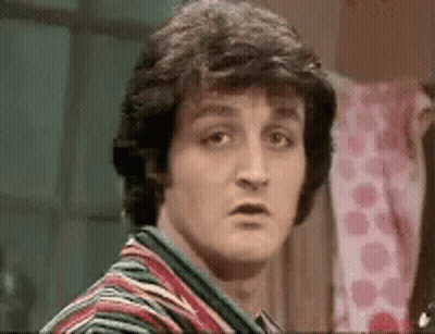 A Close Up Of A Man 'S Face With A Striped Shirt On Making A Funny Face . GIF