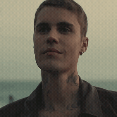 A Close Up Of A Man 'S Face With A Tattoo On His Neck And Earring GIF