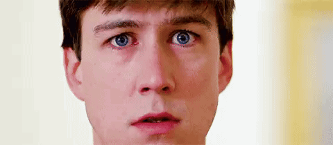 A Close Up Of A Man 'S Face With Blue Eyes Making A Surprised Face . GIF