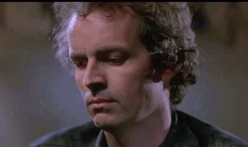 A Close Up Of A Man 'S Face With Curly Hair And A Black Shirt . GIF