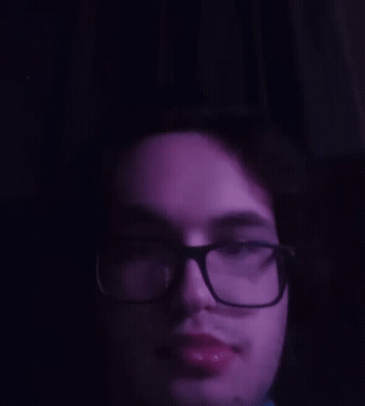 A Close Up Of A Man 'S Face With Glasses And A Purple Background GIF