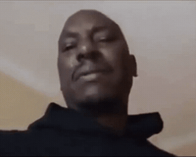 A Close Up Of A Man 'S Face With His Eyes Closed And A Black Hoodie On . GIF