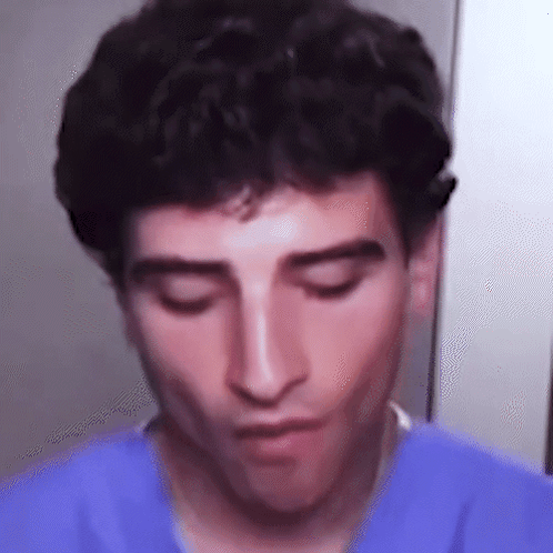 A Close Up Of A Man 'S Face With His Eyes Closed Wearing A Blue Shirt . GIF