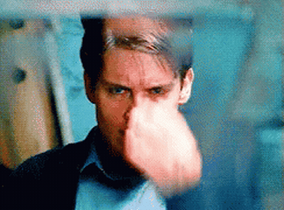 A Close Up Of A Man 'S Face With His Fist In The Air . GIF