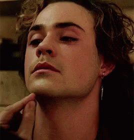 A Close Up Of A Man 'S Face With His Hand On His Chin And Earrings . GIF