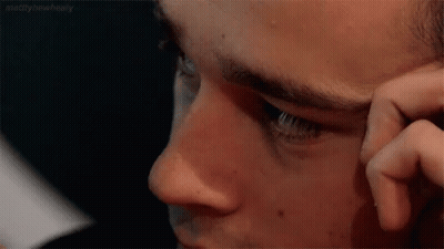 A Close Up Of A Man 'S Face With His Hand On His Face . GIF