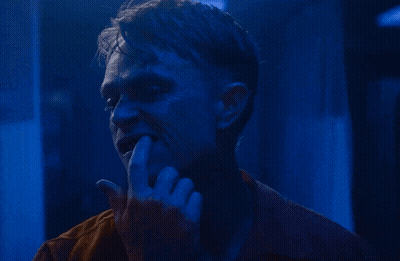 A Close Up Of A Man 'S Face With His Hand On His Mouth GIF