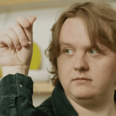 A Close Up Of A Man 'S Face With His Hand Up In The Air GIF