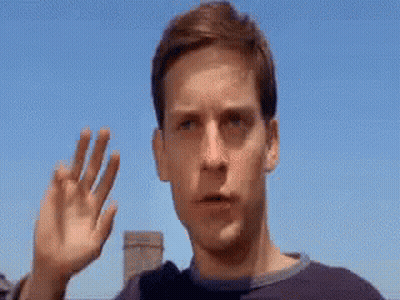 A Close Up Of A Man 'S Face With His Hand Up In The Air . GIF