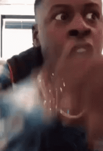 A Close Up Of A Man 'S Face With His Hands Folded In Front Of His Mouth . GIF