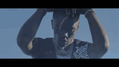 A Close Up Of A Man 'S Face With His Hands On His Head Against A Blue Sky GIF
