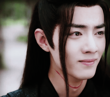 A Close Up Of A Man 'S Face With Long Hair And A Red Necklace Around His Neck GIF