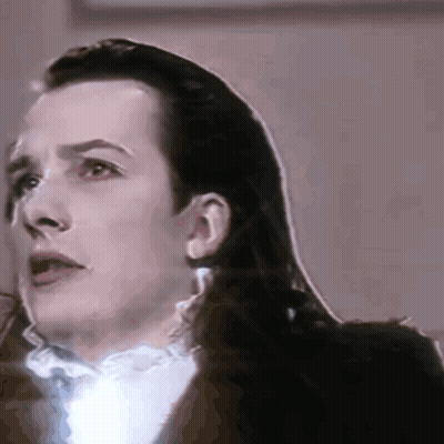 A Close Up Of A Man 'S Face With Long Hair And A White Shirt GIF