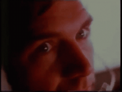 A Close Up Of A Man 'S Face With Red Eyes And A Blurred Background . GIF