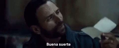 A Close Up Of A Man 'S Face With The Words `` Buena Suerte '' Written On The Screen Behind Him . GIF