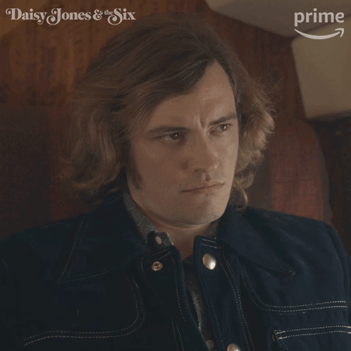 A Close Up Of A Man 'S Face With The Words Daisy Jones & The Six In The Background GIF