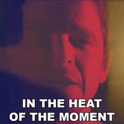 A Close Up Of A Man 'S Face With The Words " In The Heat Of The Moment " Below It GIF