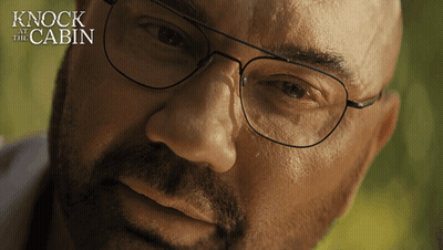A Close Up Of A Man 'S Face With The Words " Knock At The Cabin " Behind Him GIF
