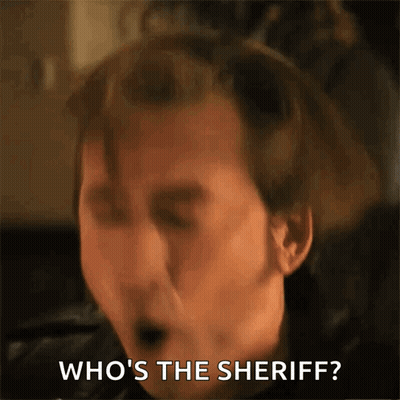 A Close Up Of A Man 'S Face With The Words Who 'S The Sheriff Behind Him GIF