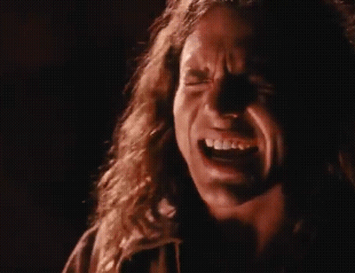 A Close Up Of A Man Screaming Into A Microphone In A Dark Room . GIF