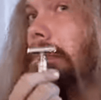 A Close Up Of A Man Shaving His Beard With A Razor . GIF