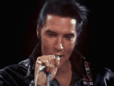 A Close Up Of A Man Singing Into A Microphone In A Dark Room GIF