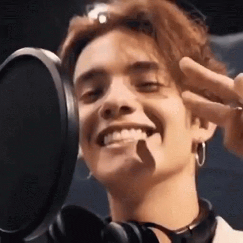A Close Up Of A Man Smiling In Front Of A Microphone . GIF