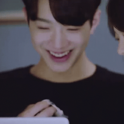 A Close Up Of A Man Smiling While Looking At A Tablet . GIF
