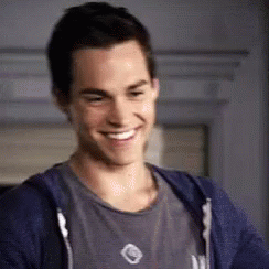 A Close Up Of A Man Wearing A Blue Hoodie And A Grey Shirt Smiling . GIF