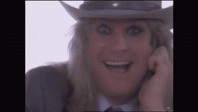 A Close Up Of A Man Wearing A Cowboy Hat And Smiling While Talking On A Cell Phone . GIF